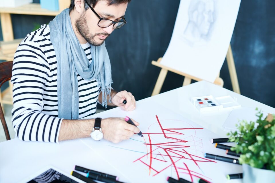 креативен мъж рисува с маркери posca